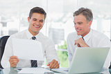 Smiling businessman listening to his intern while explaining documents