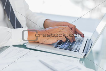 Close up on businessmans hands typing on his laptop