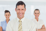 Smiling businessman posing with his colleagues on background