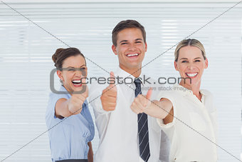Smiling colleagues posing with thumbs up