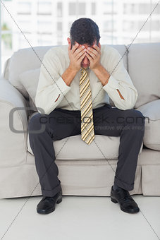 Troubled businessman sitting on sofa