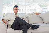Serious businessman posing sitting on sofa