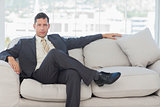 Serious businessman in suit posing sitting on sofa