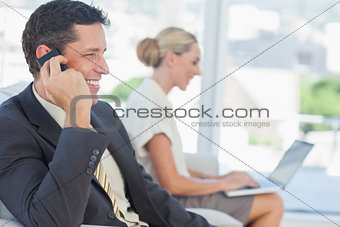 Businessman on the phone with his colleague working on computer