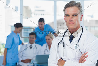 Experienced doctor posing with colleagues in background