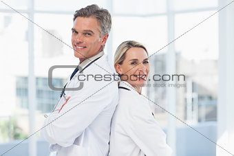 Smiling doctors posing together back to back