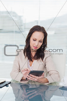 Concentrated businesswoman working on her tablet pc