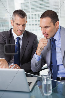 Concentrated businessmen analyzing documents on their laptop