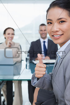 Young pretty applicant showing thumb up after obtaining the job