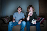 couple watching television laughing and embarrassed