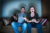 middle aged couple and dog laughing at the television