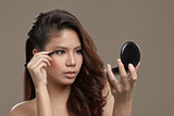 Female asian applying eye liner