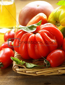 different varieties of tomato with basil on a wooden table