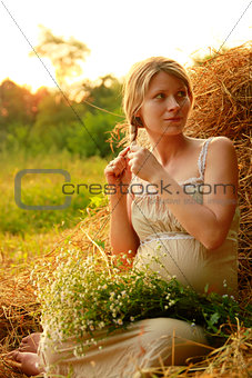 Pregnant woman on nature near the haystacks