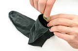 Male hand putting Euro coin into a sock