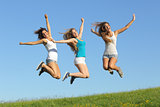Group of three teenager girls jumping on the grass
