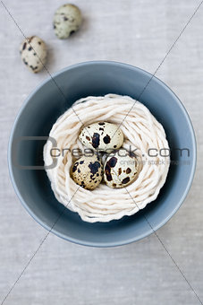 Three quail eggs in the nest with the thread on the gray plate