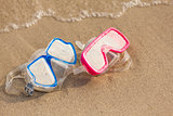 Summer time: Red and blue gogles on the sand washed by the ocean