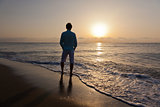 Man alone on beach watching the sunset