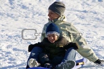 Happy Mother and Son Sledding down the Hill