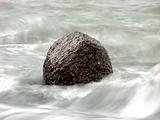 Single rock surrounded by waves