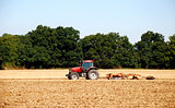Tractor and harrow cultivating the soil
