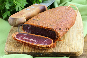 cured meat - basturma in hot pepper (paprika) on a cutting board