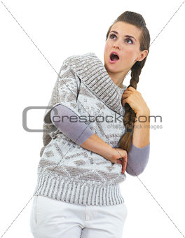 Surprised young woman in sweater looking on copy space