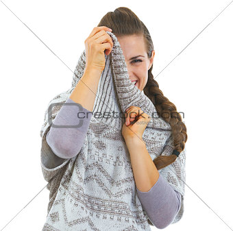 Smiling young woman hiding in sweater neckline