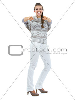 Full length portrait of smiling young woman in sweater pointing 