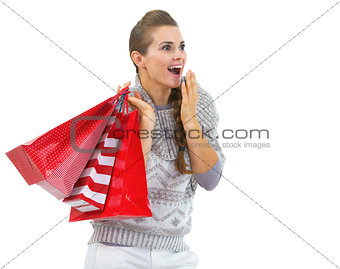 Surprised young woman in sweater with christmas shopping bags lo