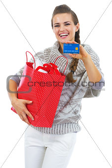 Happy young woman in sweater with christmas shopping bag showing