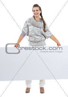 Full length portrait of smiling young woman in sweater holding b
