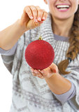 Closeup on christmas ball in hand of young woman in sweater