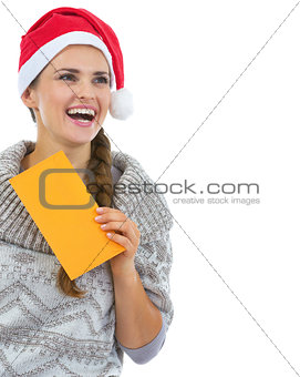 Happy young woman in sweater and christmas hat with letter looki