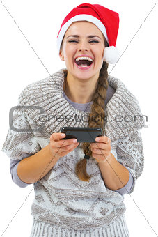 Happy young woman in sweater and christmas hat reading sms