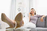Smiling young woman talking cell phone in living room