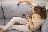 Thoughtful young woman sitting on couch with credit card and pho