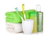 Two colorful toothbrushes, cosmetics bottles and towels