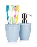 Four colorful toothbrushes and liquid soap