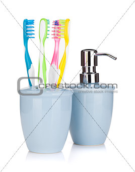Four colorful toothbrushes and liquid soap