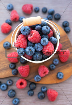 Fresh blueberries and raspberries in a  bucket 