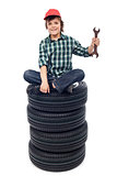 Young mechanic with tires and spanner