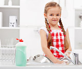 Little girl washing dishes in the kitchen