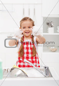 Happy little girl washing the dishes