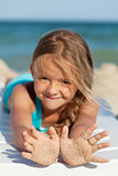 Happy little girl with sandy hands on the beach