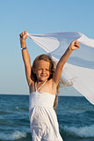 Little girl on sea shore playing with a kerchief in the wind