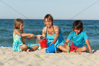 Woman and kids on the beach - playing with sand