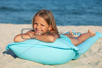 Little girl with inflatable mattress or raft on the beach
