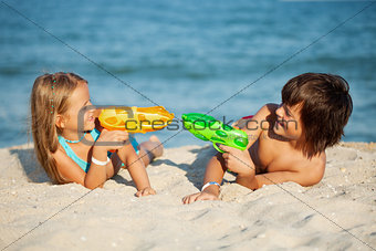 Kids having fun with water pistols on the beach